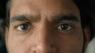 Ekstrem makro yakın çekim yarı erkek yüzü kahverengi gözler ciddi mutsuz etnik kökenli adam kameraya bakıyor göz ameliyatı lazer görme düzeltme göz doktoru konsepti