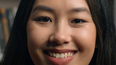 Yakın plan kadın yüzü mutlu Asyalı bayan müşteri beyaz dişleriyle gülümseyen diş hekimliği hizmeti veren diş sağlığı kliniğinden memnun olan kameraya bakıyor. Yüksek