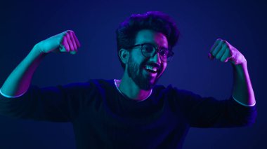 Komik Hintli zayıf adam el ele tutuşuyor kas pazıları spor güçlü vücut geliştirici ultraviyole neon arka plan gururlu şampiyon verimli güvenlik kodlama seviyesini yükseltti