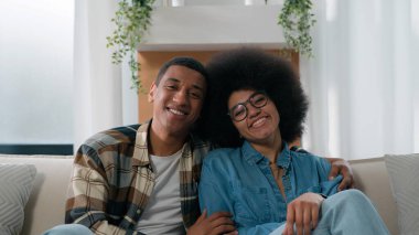 Portre mutlu aile Afro-Amerikan çift birbirlerine sevgi dolu bakıyorlar evli koca koca erkek sevgili kadın kız arkadaş kucaklaşıyorlar kamera ev sahiplerine bakıyorlar.