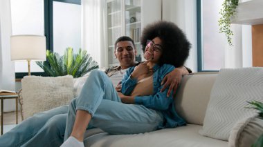 Afrika kökenli Amerikalı eşler çift kadın kadın erkek kanepede kendi evinde oturup aile meselelerini tartışırlar gülüşmeler, gülüşmeler, kucaklaşmalar, karı koca muhabbetleri.