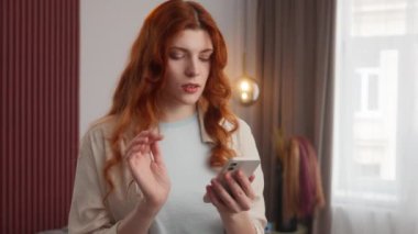 Şaşırmış beyaz kadın, kızıl saçlı, ekranda yazan, cep telefonlu, daktilo kullanan, akıllı telefonlu, hayran olunan model internette inanılmaz şeyler okuyor. İnternet haberlerinde şok etkisi yaratıyor.