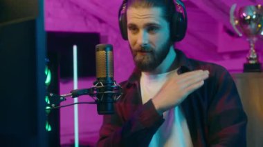 Mutlu Kafkasyalı erkek blogcu adam mikrofoncu mikrofoncu kupa bağımlısı blogcu blogcu e-sporcu olumlu oyuncu etkisinde övünen neon dansı evinde kutlama yapıyor.