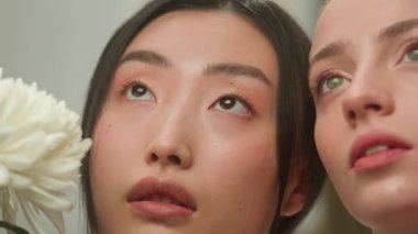 İki şehvetli zarafet çok ırklı güzel kız çeşitliliği doğal güzellik kozmetik dermatolojisi modelleri çok ırklı Japon Asyalı Çinli beyaz kadınların yüzlerinin yanında çiçek açması.