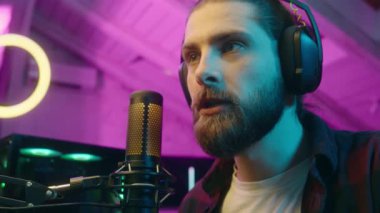 Odaklanmış memnun beyaz adam oyuncu akışı yorumlama oyunu mikrofonla bak erkek sanal oyun stratejisi online sanal spor bağımlısı gergin oyuncu blogcu çığlıkları başarılı bir maç galibiyeti evi kazandı