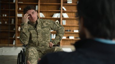 Gergin, asabi, kafkas asker, engelli, erkek, kamuflaj, savaş üniforması, asker, tekerlekli sandalyedeki eski asker, psikolog, ofiste travma sonrası stres bozukluğunu anlatıyor.