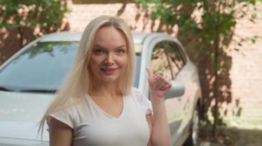 Neşeli gülümseyen Kafkasyalı kiralama servisi müşterisi kız sürücü alıcı kameraya bakıp araba anahtarlarını gösteren bir gülümseme gösteriyor şehir merkezinde yeni test sürüşü satın alıyor