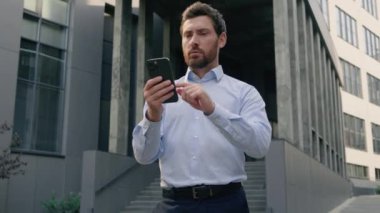 Akıllı telefon başarısı İnternet kazancı Kumarhane bahsi mutlu mutlu Kafkas işadamı işvereni orta yaşlı iş adamı erkek yetişkin adam şehirde cep telefonunu online olarak kazanarak kutluyor