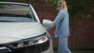 Gülümseyen beyaz kadın araba satıcısı kadın, pozitif kadın sürücü, kiralık araba kapısı açık, araçta oturuyor. İş kadını şehirde güvenli bir yolculuk için yeni elektrikli araba satın alıyor.