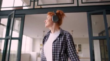 Mutlu Kafkasyalı kadın pozitif kız evde kaygısız neşeli kadın dans ediyor zıplayarak eğleniyor kablosuz kulaklıklarla müzik dinliyor internette piyano çalıyormuş gibi yapıyor.