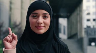 Mutlu bir portre gülümseyen Müslüman iş kadını, İslami iş kadını, kentte siyah tesettürlü bir iş kadını, bir parmağını gösteren bir iş adamı. Fikir çözümü için kafa yoran bir karar. Açık havada düşünmek.