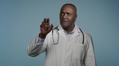 Odaklanmış Afro-Amerikan erkek doktor erkek profesyonel sağlık çalışanı mavi stüdyoda çalışan, modern yenilikçi teknoloji kullanarak üç boyutlu hologram teşhisi üzerinde çalışan ellerini hareket ettirdi.