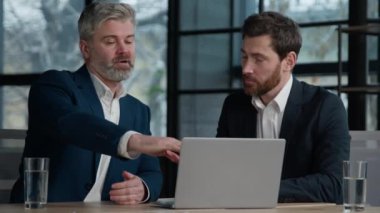 Olgun Kafkasyalı deneyimli bir adam profesyonel çalışan banka danışmanı erkek müşteriye danışmanlık yapıyor. Ofiste sunum yapıyor. İş ortakları online proje hakkında konuşuyor.