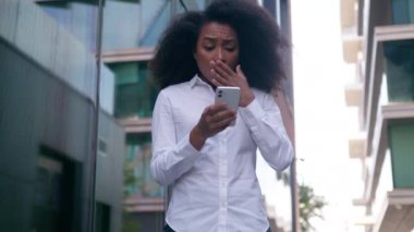 Şok olmuş, afro-amerikalı kadın, iş kadını, dışarıda cep telefonu, akıllı telefon, kötü haber, hata, işçi, şehir merkezindeki girişimci.