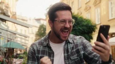 Mutlu, beyaz, erkek iş adamı. Harika bir cep telefonu mesajı alıyor. Evet diye bağırıyor.