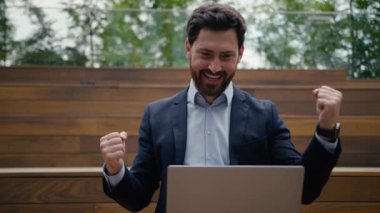 Mutlu iş adamı Kafkasyalı erkek işveren yatırımcı sevinçli girişimci zaferi kutluyor zafer kazandı online bahis dizüstü bilgisayarı kazandı bilgisayar kazananı dışarıda eğleniyor evet şehir dışında