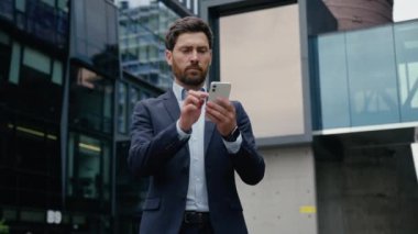 Kafkasyalı bir adam cep telefonu veri bağlantılarını araştırıyor şehir merkezindeki erkek işveren yetişkin işadamı yatırımcı adam akıllı telefon ekranı online uygulama bağımlısı açık hava