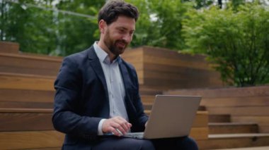 Kafkasyalı mutlu erkek iş adamı çevrimiçi iş adamı dışarıda çalışıyor dizüstü bilgisayarlara bakıyor para kazanılıyor zafer teklifi şehirde kutlanıyor