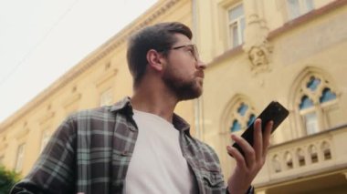 Kafkasyalı adam akıllı telefonu elinde tutuyor. Adresi arıyor. Kayıp şehir. Erkek turist turizmine cep telefonu GPS 'i kullanarak bakıyor.