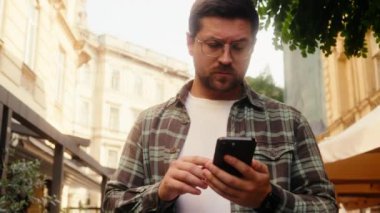 Kafkasyalı erkek turist kafası karışmış gezgin açık havada cep telefonu navigatörüyle yürüyen kayıp şehir telefonu GPS haritası online uygulama hedef adresi arama seyahat rehberi