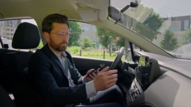 Şehirdeki modern elektrikli otomobil kullanan bir iş adamı, mobil mobil mobil GPS uygulaması ve trafik sıkışıklığı nedeniyle kafası karışmış sürücü yolu navigasyon hatası yüzünden endişeli.
