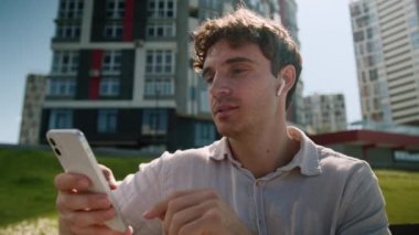 Kafkasyalı erkek adam dışarıda oturuyor cep telefonu teknolojisi cihazları kulaklıklar müzik keyfi müzik listesi müzik listesi kulaklıkları iş adamı mp3 kablosuz şarkı hafta sonu aleti