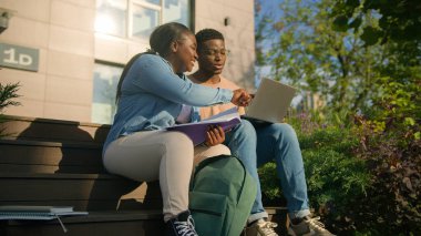 İki Afrikalı öğrenci, liseli kız öğrenci, şehir parkının dışındaki kampüste, bankın dışında, konuları tartışıyor, ödevleri tartışıyor üniversite sınavlarına hazırlanıyor, sınavlara hazırlanıyor, dizüstü bilgisayar eğitimi kullanıyor.