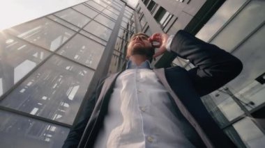 Alt görüşe göre Kafkasyalı orta yaşlı işadamı işadamı işveren erkek yatırımcı cep telefonu görüşmesi yapan girişimci şirket binası yakınlarındaki telefon görüşmesi kentsel gelişim yatırımına yatırım yapıyor.