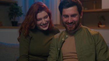 Mutlu gülümseyen Kafkasyalı koca karı karı karı evli çift kanepe ev sörf bilgisayarı romantik bir akşam internette dolaşarak internetten sipariş edilen dizüstü bilgisayarla alışveriş yapıyorlar.