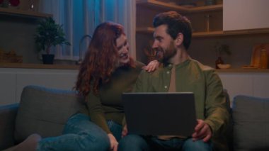 Kafkasyalı evli bir çift, aşık bir erkek ve karı koca, akşam rahat bir koltukta oturup sohbet ediyorlar ve dizüstü bilgisayarla online mağaza biletlerini almayı planlıyorlar.