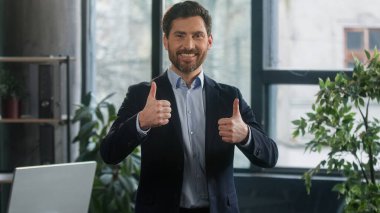 Focused adult caucasian man recruiting agent standing in office making notes writing checklist businessman conducts inspection write strategic plan showing thumb up gesture approval best choice sign