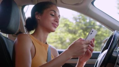 Cep telefonu akıllı telefonu kullanan Afrikalı Amerikalı kadın gülümseme ağı sosyal medya mesajları teknoloji kadın otomobil şoförü araba sahibi iş kızı park yeri sahibi