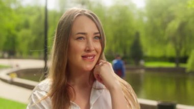 Avrupalı bir kadın dudaklarını ısırıyor gülümseyerek flört ediyor yüz ifadesini çekici güzellik şehrini işaret ediyor moda duygusal park kadınlarıyla iletişim kuruyor pozitif beklenti içindeki kız.