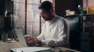 Beyaz bir adam yetişkin bir CEO 'su. İnternette orta yaşlı bir işadamı. Modern ofis yöneticisinde dizüstü bilgisayar yazıyor.