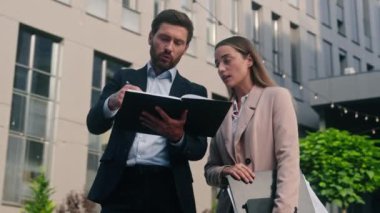 İki başarılı iş ortağı Kafkas işadamı, erkek, erkek, iş kadını, kadın, girişimci, şehirde konuşan yöneticiler kağıt dökümanları şehir binası hakkında konuşuyor.