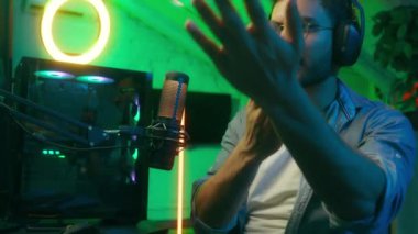 Kapalı mekanda modern neon video oyunu. Kafkasyalı, kulaklıklı, sinirli, sinirli, sinirli, sinirli, sinirli, konuşan, mikrofon arızası internet akışı.