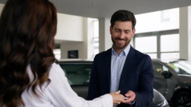 Kadın kadın danışman kadın tüccar galeride yeni araba anahtarlarını bir grup erkeğe, iş adamına, müşteri alıcısına, kredi bankası test sürüşü satın almak için lüks otomobil satın alan erkeklere veriyor.