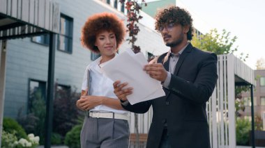 Hintli Arap erkek işadamı, elinde belgeler olan işadamı. Şirketler, şehir merkezinde çok ırklı iş adamlarıyla yürüyen Afrikalı Amerikalı kadın iş kadınıyla sonuç planlarını tartışıyor.