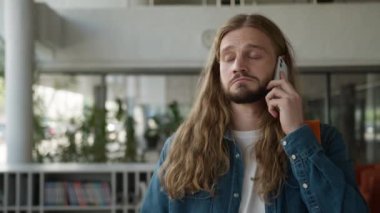 Ciddi bir beyaz erkek lisede erkek öğrenci üniversite akademisi koridorunda kapalı alanda cep telefonu konuşmaları problem tartışmaları akıllı telefon iletişim çalışmaları.