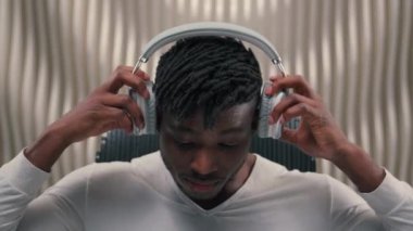 Fütürizm Afrikalı Amerikalı erkek programcı erkek tasarımcı siber veri tasarımcısı beyaz fütüristik odada kapalı mekanda modern teknoloji kablosuz kulaklıklara bağlandı.