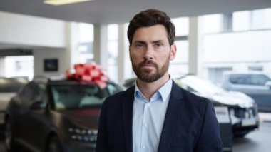 Mutlu Kafkasyalı adam satış müdürü menajer kuaför araba galerisi araba galerisi yeni araba büyük kırmızı yay alıcı müşteri erkek müşteri müşteri sahibi lüks araç kiralama hizmet kiralama mağazası gülümsüyor