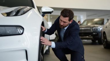 Tekerlek kalite kontrol lastiklerine dokunan beyaz adam yeni araba otomobil otomobili alıcısı test sürüşü kiralama servisi müşteri erkek satın alma, nakliye, alışveriş ve onarım elemanı seçiyor.
