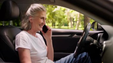 Mutlu, beyaz, neşeli, yaşlı, yaşlı, yaşlı kadın gülümseyen, olgun araba şoförü, büyükannesi cep telefonuyla konuşan, akıllı telefonlardan konuşan, şehirdeki otomobille konuşan, yaşlı kadın.