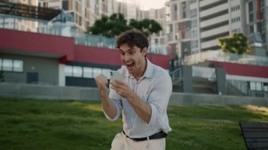 Cep telefonlu mutlu Kafkasyalı adam, akıllı telefon zaferini kazandı. Başarılı oldu. Erkek iş adamı duyguları.