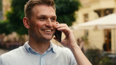 Kafkasyalı gülümseyen adam yetişkin işadamı neşeli erkek turist gezgin cep telefonuna cevap ver açık hava cep telefonu verileri cep telefonu bağlantıları cep telefonu sohbet gülümsemesi şehir turizminde Avrupa seyahati