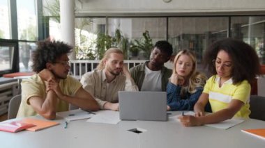 Çok ırklı öğrenciler, beş sınıf arkadaşı, Afrikalı Amerikalı erkekler, erkek, beyaz kadın kızlar, birlikte üniversite kütüphanesinde dizüstü bilgisayar okuyorlar.