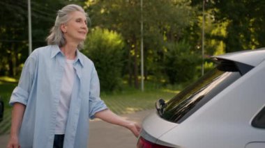 Mutlu gülümseyen Kafkasyalı yaşlı yaşlı yaşlı kadın yaşlı kadın büyükanne araba şoförü kadın müşteri müşteri alışverişi araba bagajı yükleme alışveriş torbaları şehir caddesinde alışveriş mağazası alışverişi