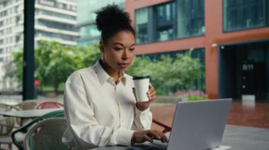 Bilgisayarda dizüstü bilgisayar yazan Afro-Amerikalı kadın internet yöneticisi kız iş kadını iş kadını e-ticaret açık havada kahve içen serbest çalışan işveren kupası şehri.