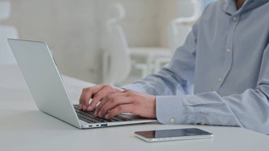 Hareket eden Arap asıllı Hintli iş adamı Laptop 'ta çalışan erkek iş adamı iş adamı programcısı bilgisayar programı yazılımı programcısı ofis masasında cep telefonuyla uzaktan kumanda işi