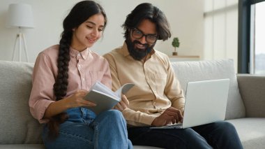 Çok ırklı bir çift olan Arap yetişkin erkek ve kadın gazete okuyorlar. Faturaları ödüyorlar. Ev kredisi ödemeleri planlıyorlar.